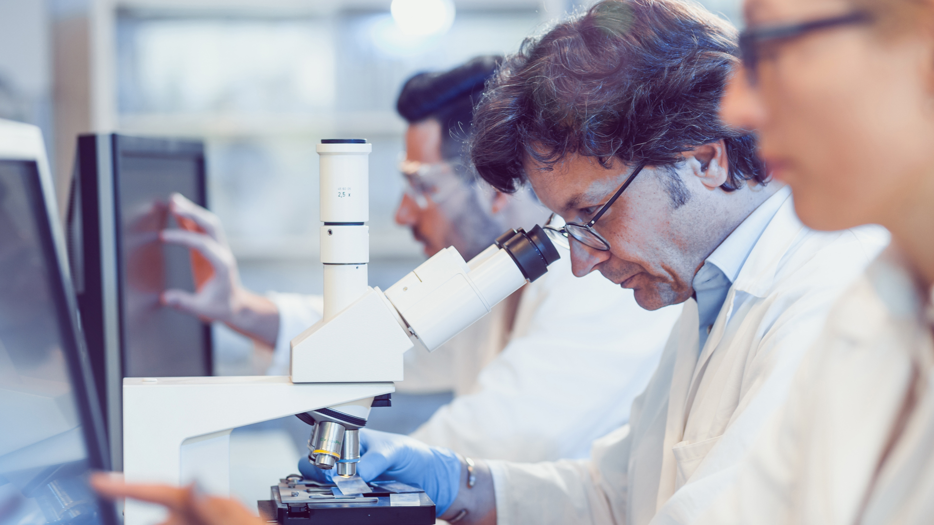 A group of people in lab coats analyzing data on a computer screen.